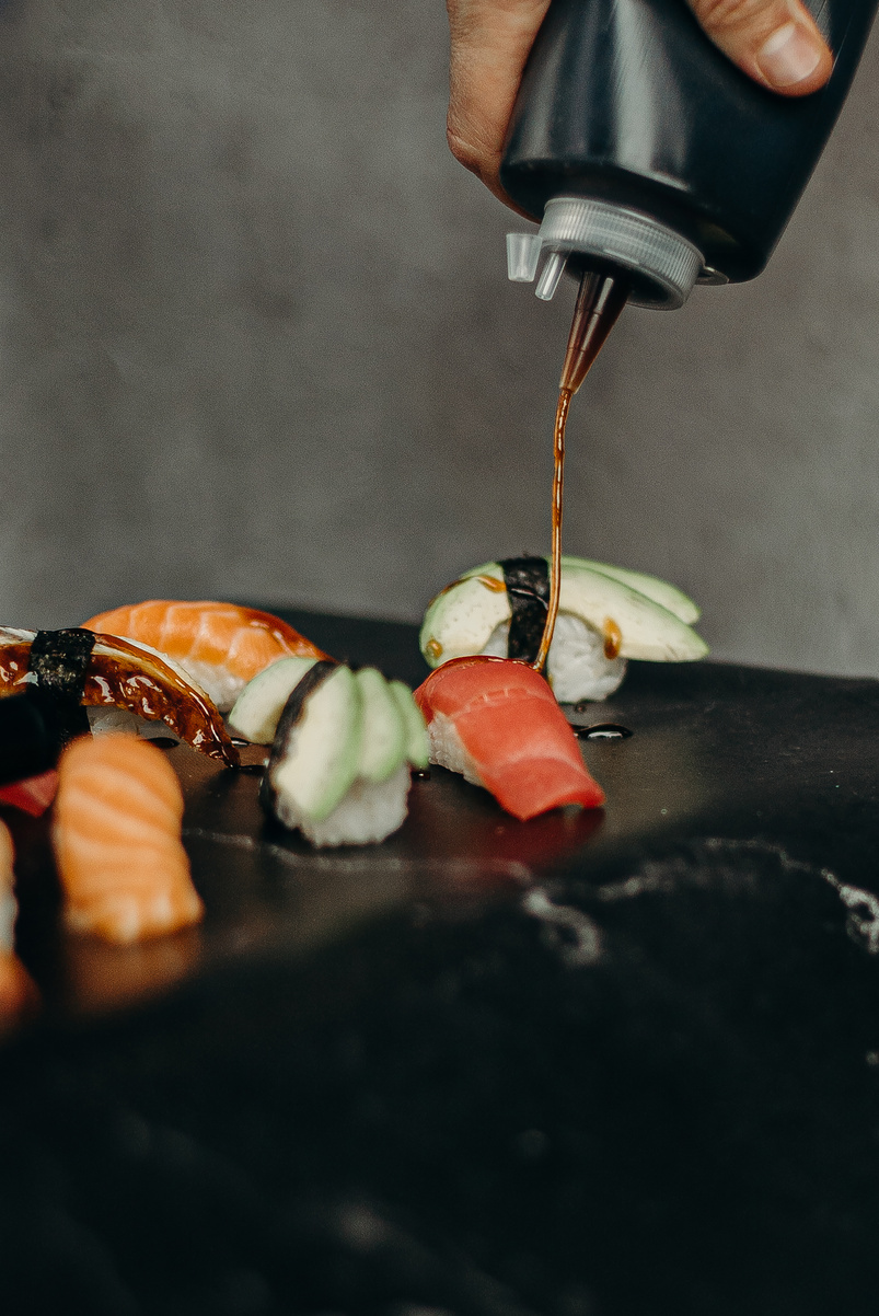 Person Putting Sauce On A Sushi Dish